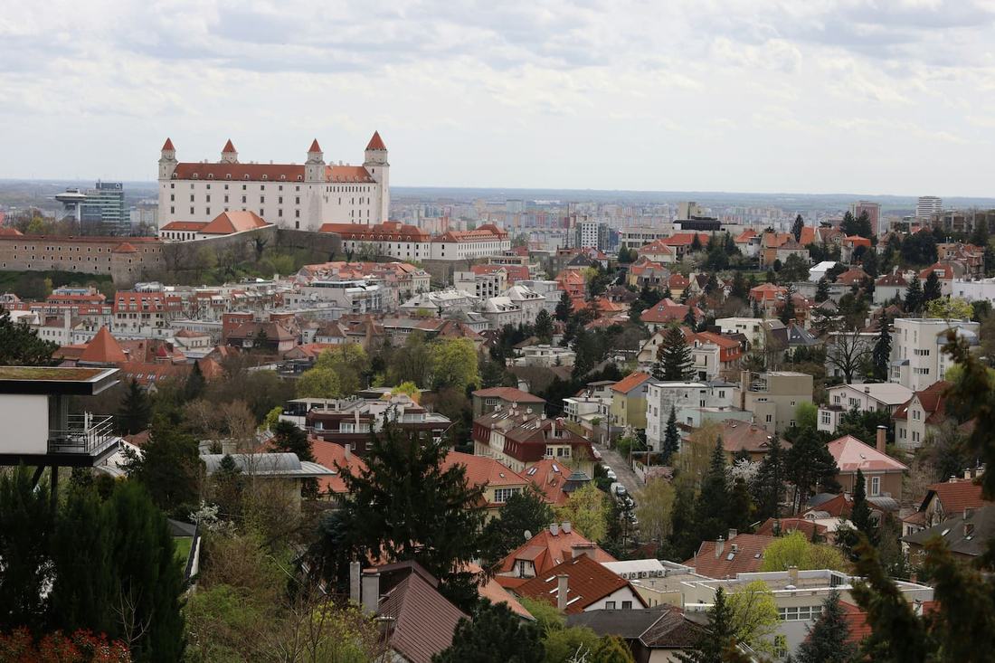 Bratislava Castle with its four corner towers above red-roofed houses and green hillside gardens