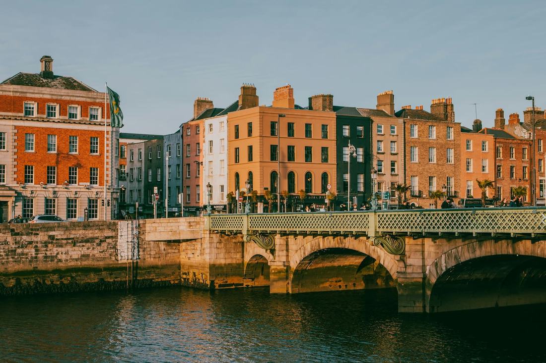 Georgian brick buildings along the River Liffey quays in Dublin in evening light, with a stone bridge over the river