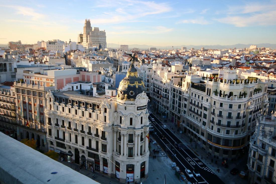 The domed Metrópolis Building at the start of Gran Vía in Madrid, with ornate apartment blocks and the city stretching to the horizon