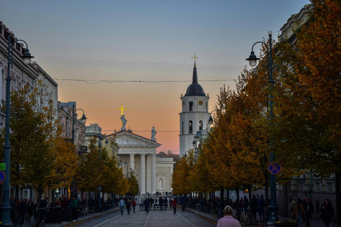 Gediminas Avenue in Vilnius in autumn, lined with golden trees and leading to the Cathedral and its bell tower at sunset