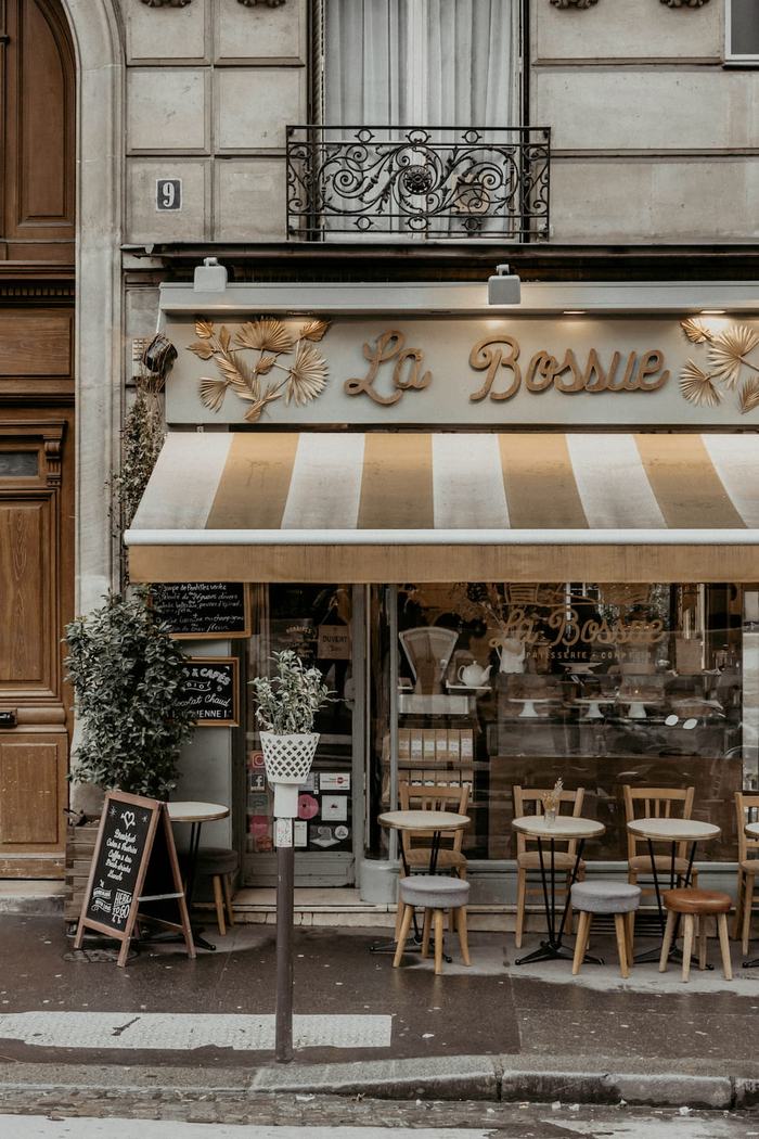 A Parisian café with a striped awning and bistro chairs on the pavement