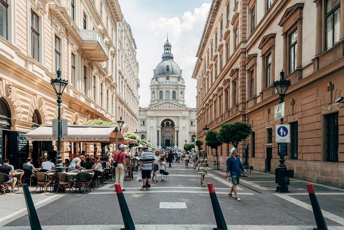 A pedestrian street with café terraces leading to the dome of St Stephen's Basilica in Budapest