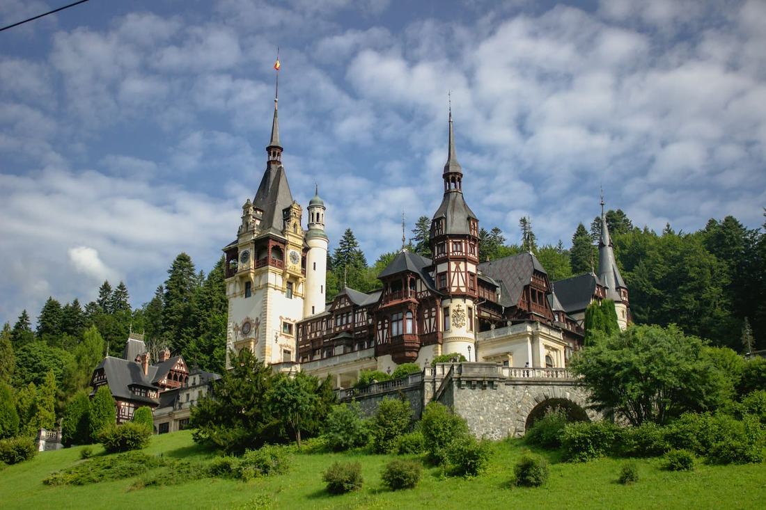 Peleș Castle in Sinaia, with its towers and timber-framed façades set among Carpathian pine forest