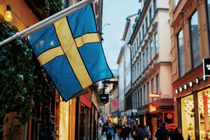 Swedish flag over a cobbled shopping street in Stockholm's Old Town